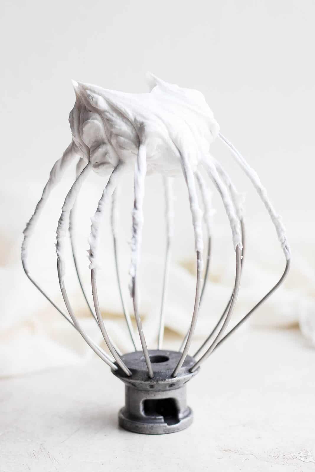 Dairy free whipped cream on a whisk attachment for a mixer.