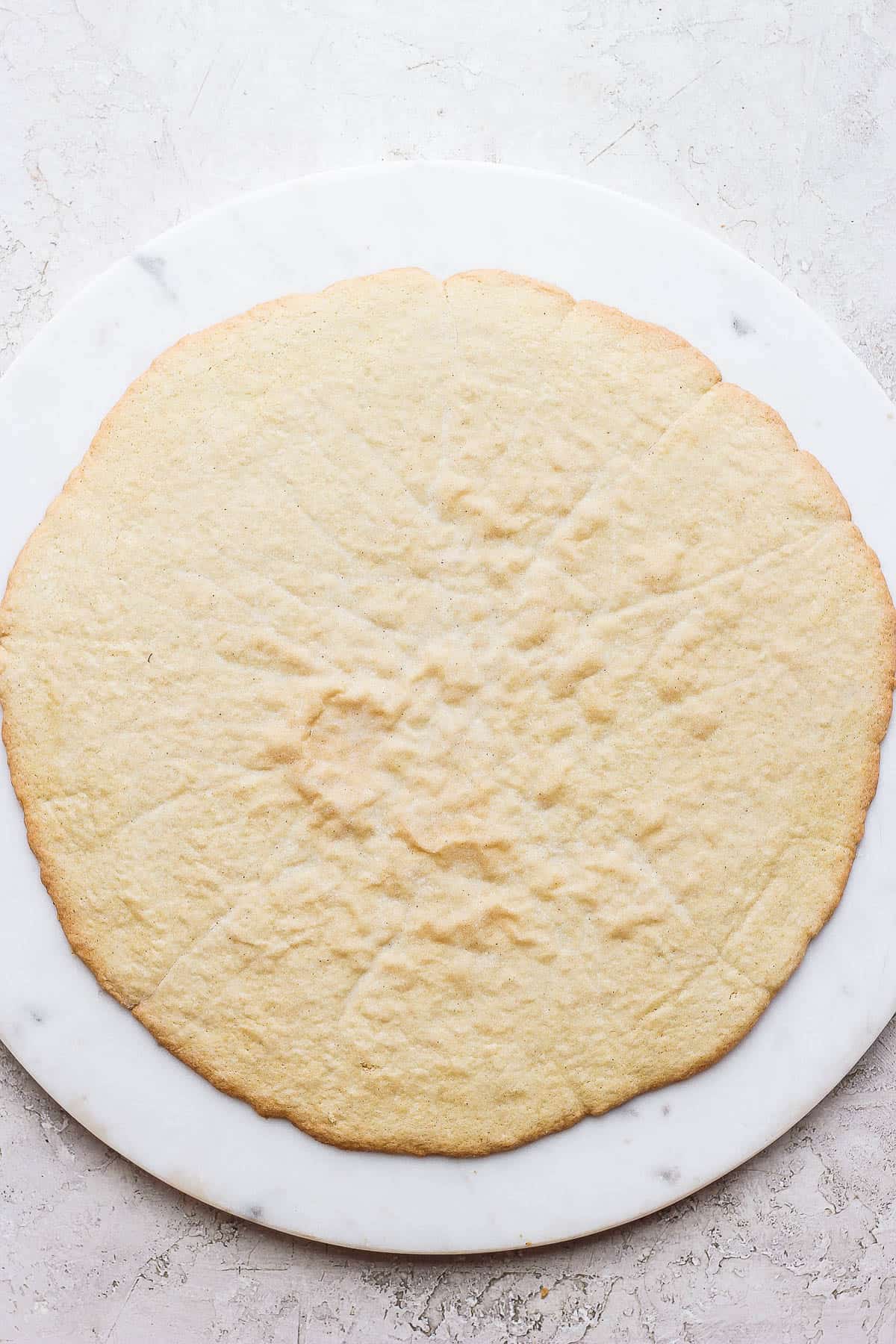 A large sugar cookie on a marble board. 