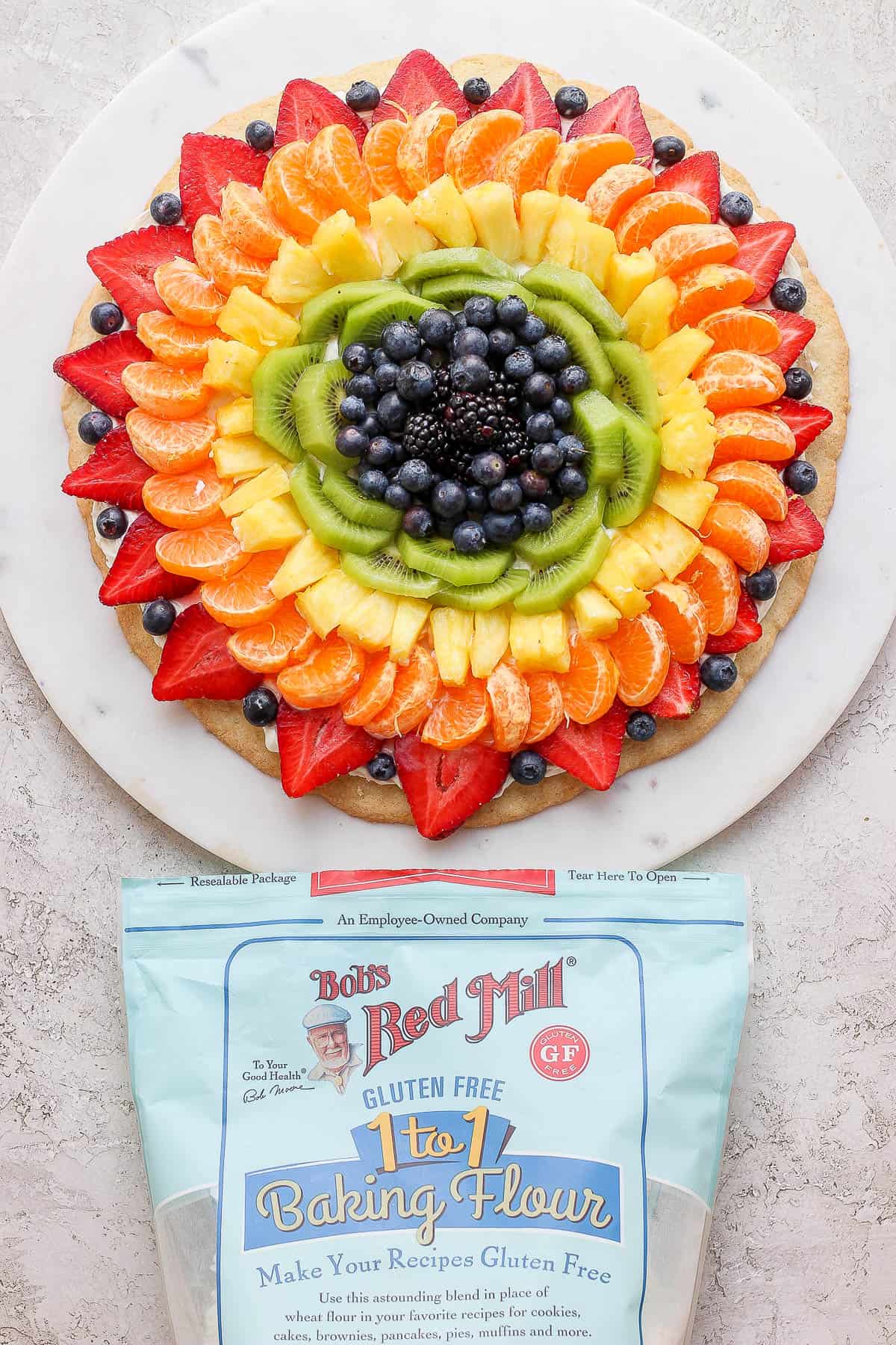 A fruit pizza and a package of Bob's Red Mill gluten free flour. 