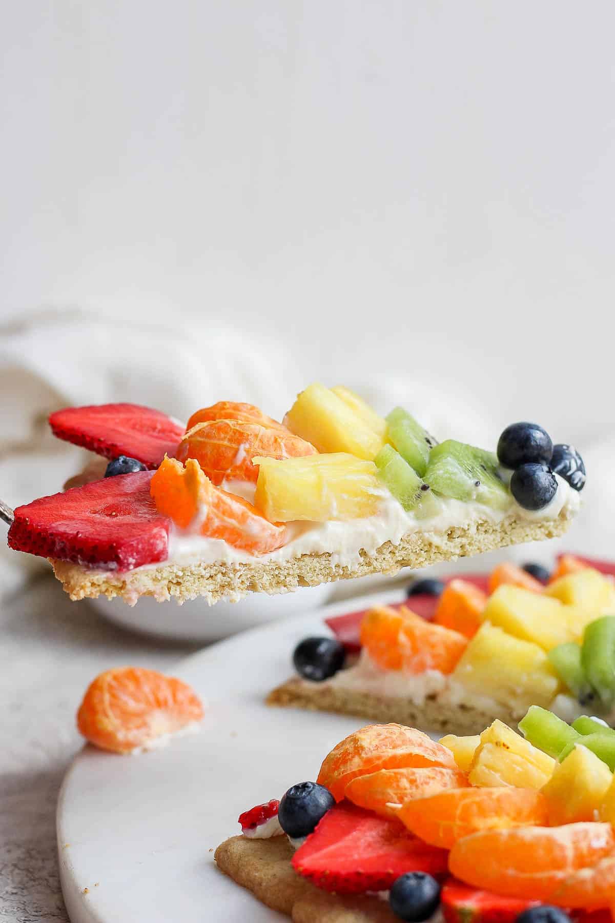 A slice of fruit pizza being lifted up. 