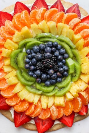 Fruit pizza on a while marble board.