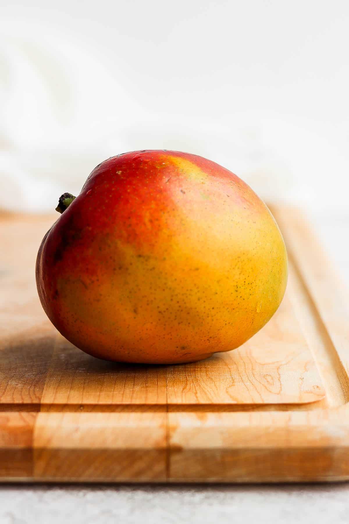 A ripe mango on a cutting board.