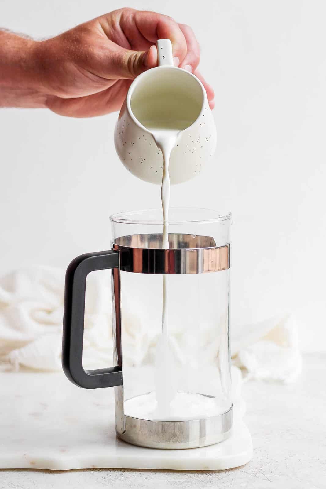 Someone pouring milk into a French press. 