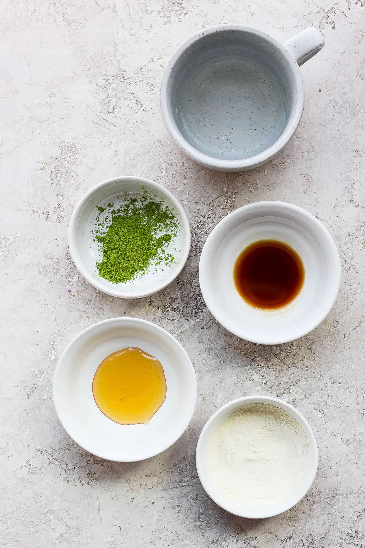 Ingredients for a matcha latte in small bowls. 