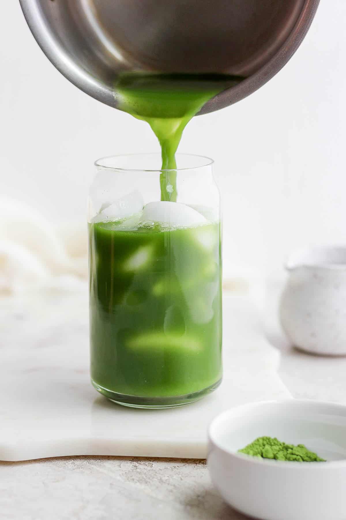 Someone pouring matcha over ice. 