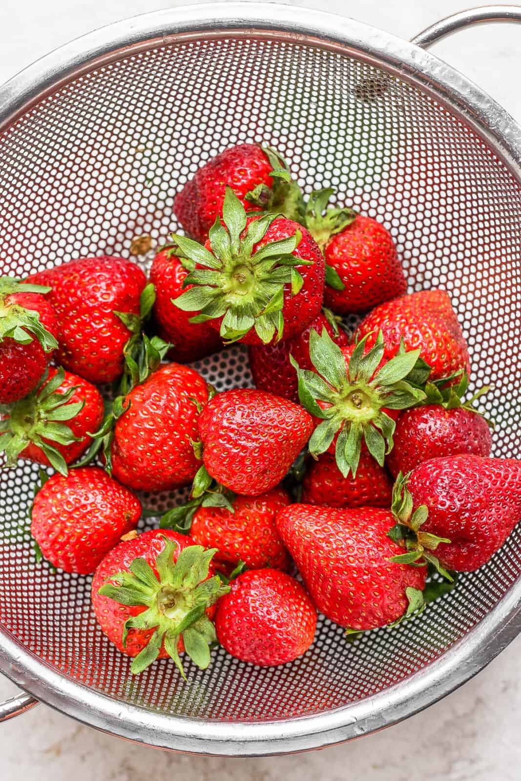 Whole strawberries in a colander.