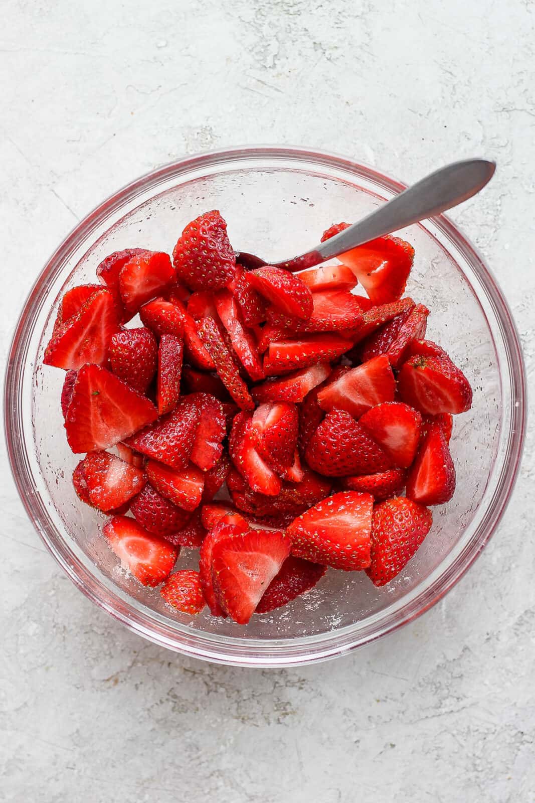 Sliced strawberries and coconut sugar mixed together in a bowl.