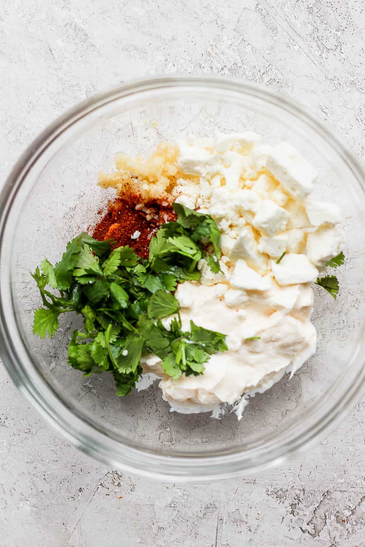 Mayo, feta, cilantro, and spices in a mixing bowl.