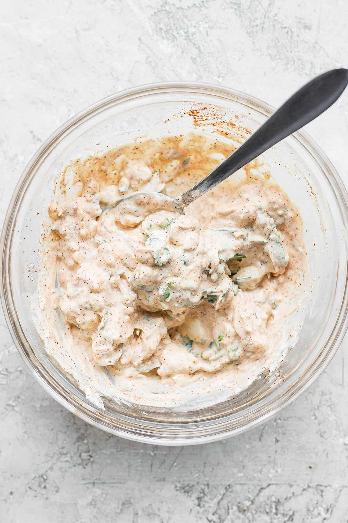 Bowl of mayo mixture to put on corn in a bowl with spoon sticking out.