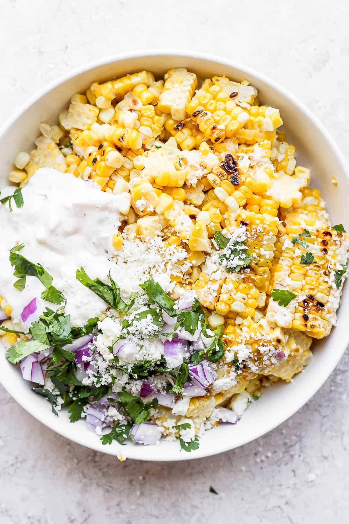 All of the ingredients for mexican street corn salad in a white bowl.