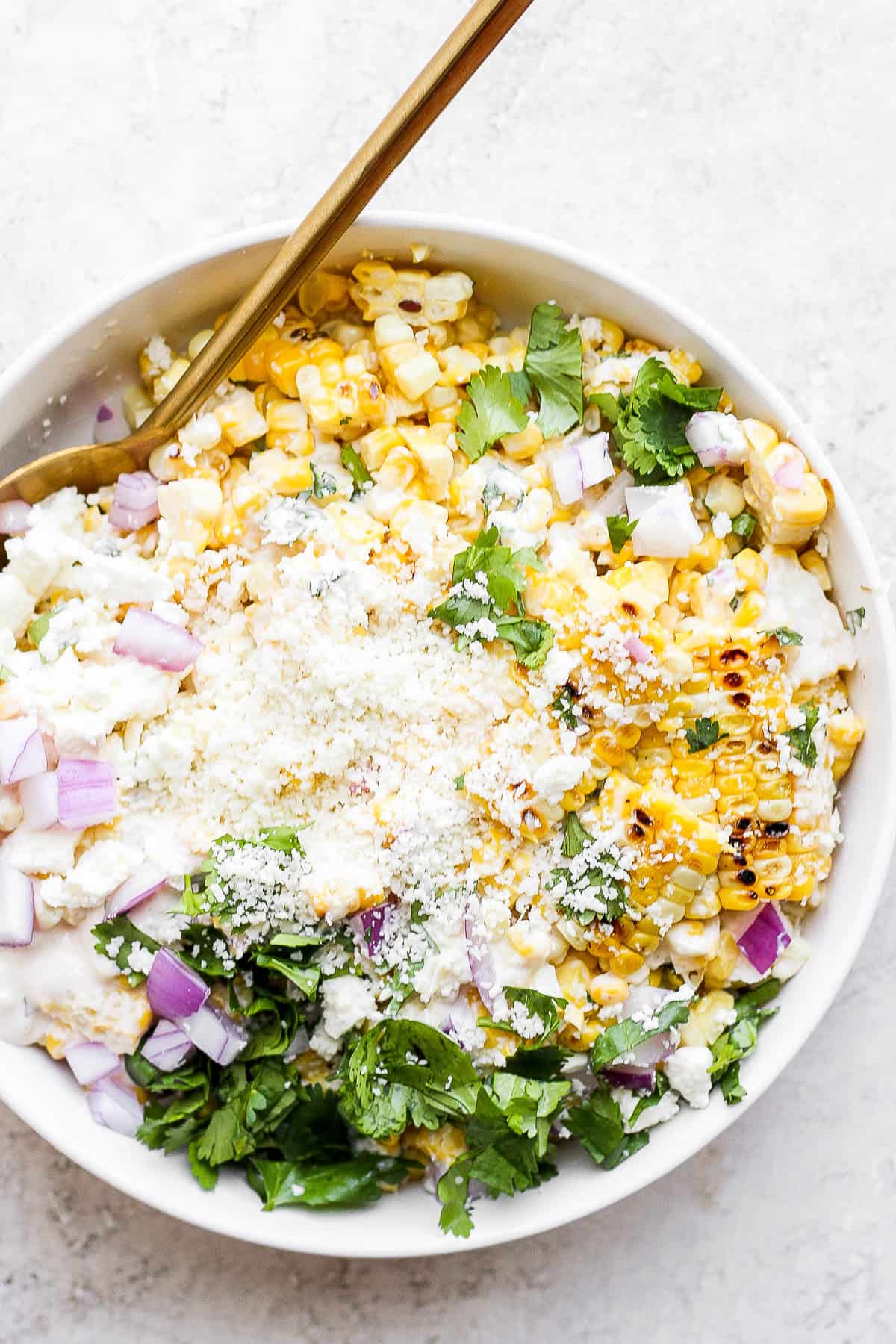 A large white bowl of Mexican street corn salad.