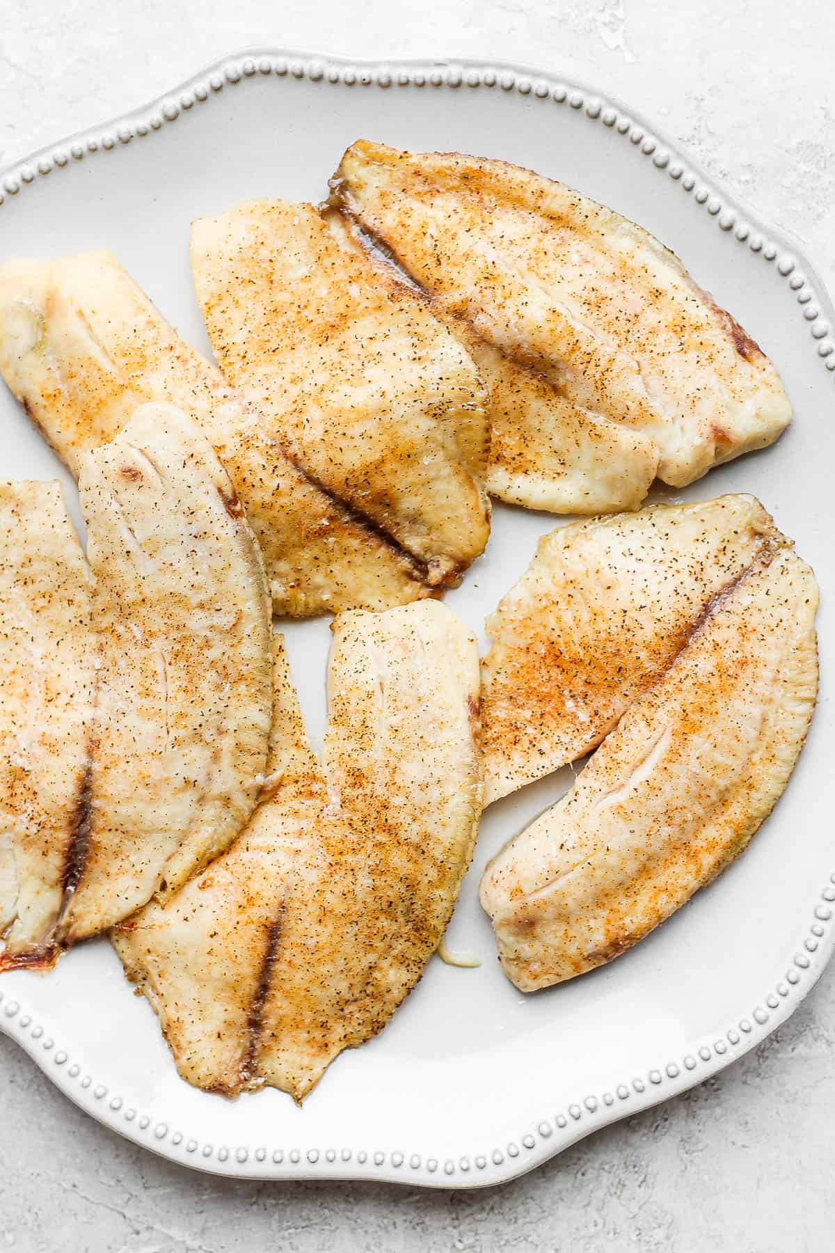 Baked tilapia fillets on a plate.