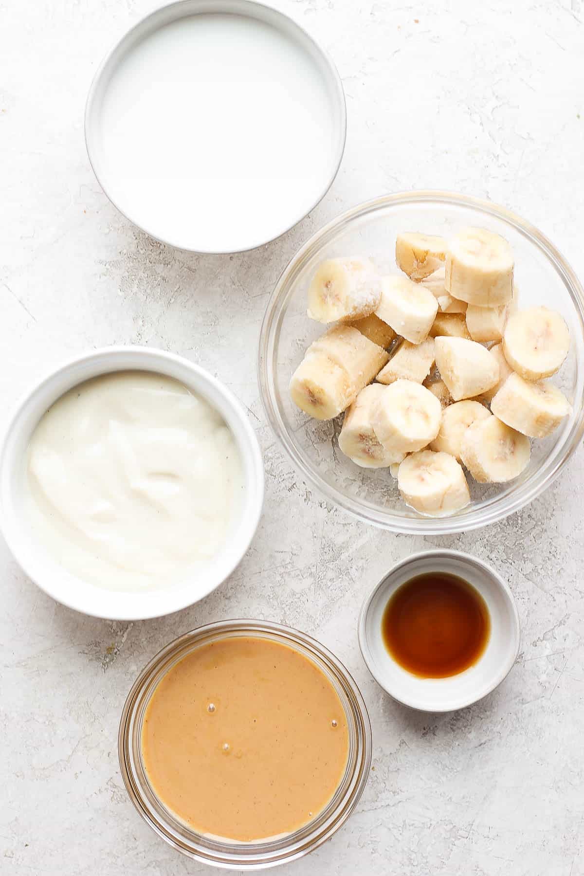 Peanut butter banana smoothie ingredients in small dishes.