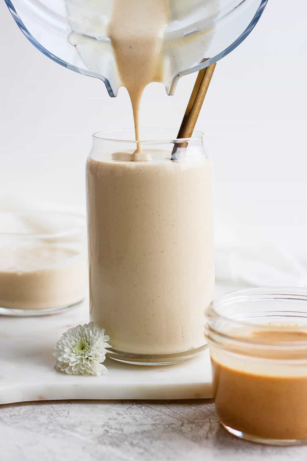 Peanut butter banana smoothie being poured from a blender to a glass.
