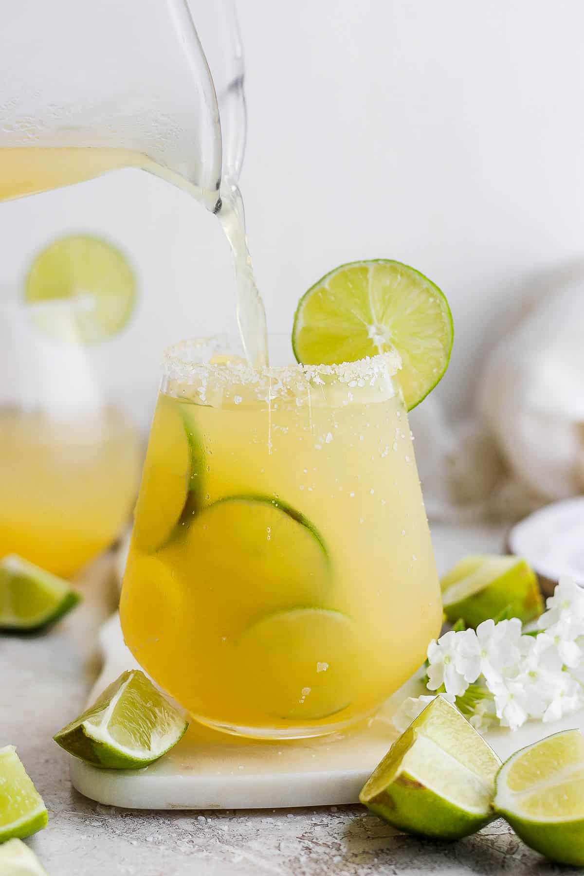 Someone pouring margarita into a salt-rimmed glass. 