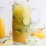 A pitcher of margaritas with limes and ice.