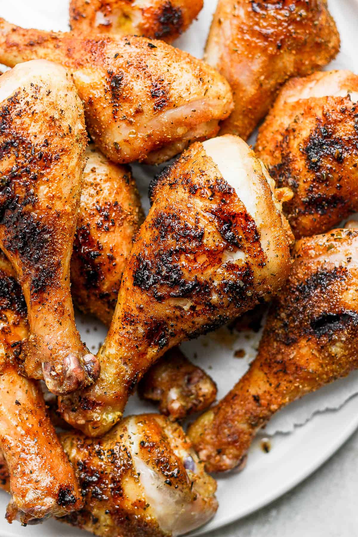 A plate full of smoked chicken legs with crispy skin.