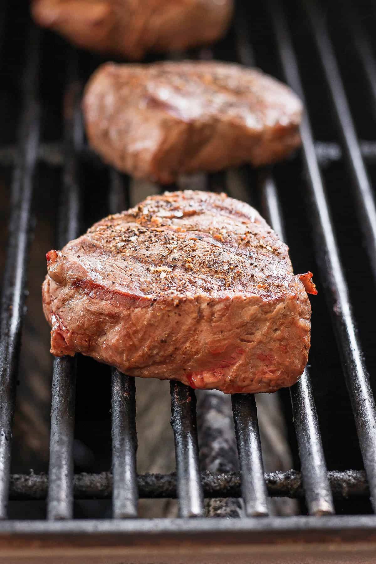 Three steaks on the grill. 