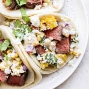 Grilled steak on street taco tortillas with Mexican street corn and other taco toppings.