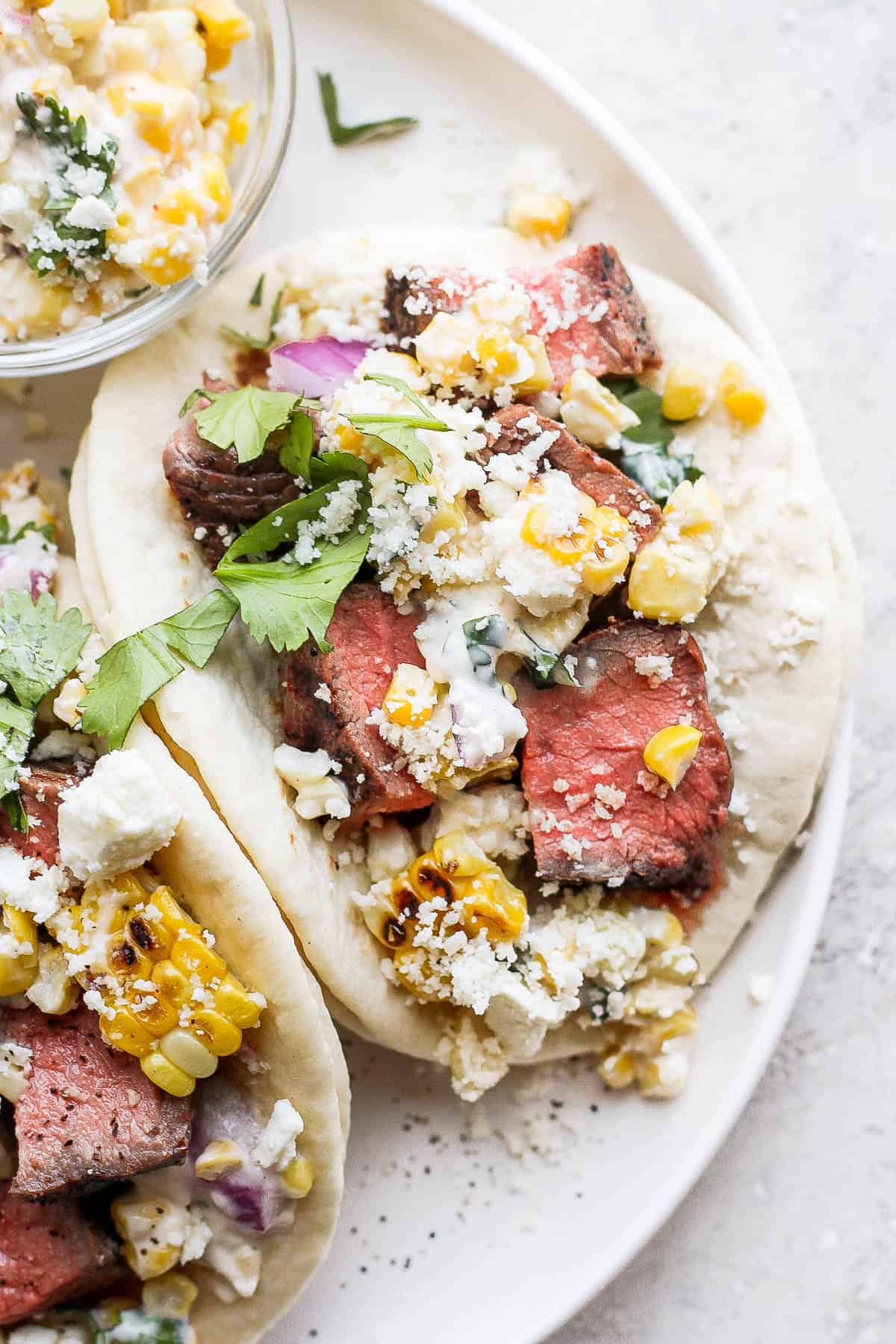 Close up shot of a steak taco on a plate with all of the toppings.