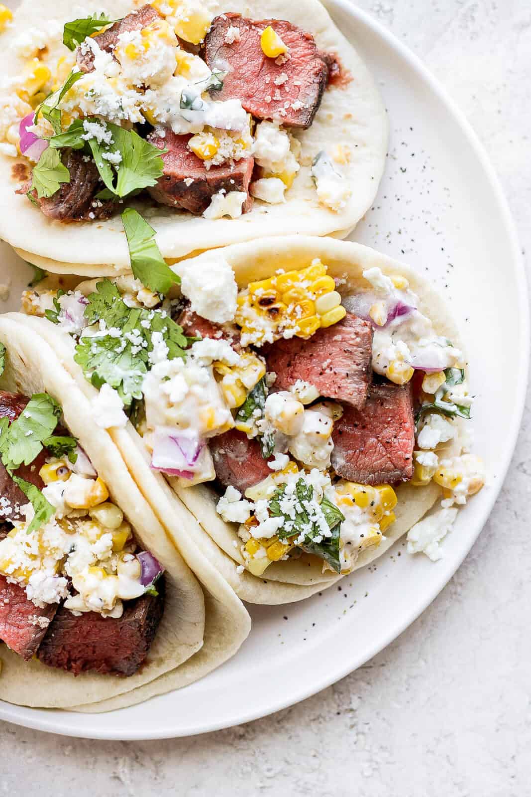 Three steak tacos on a plate. 