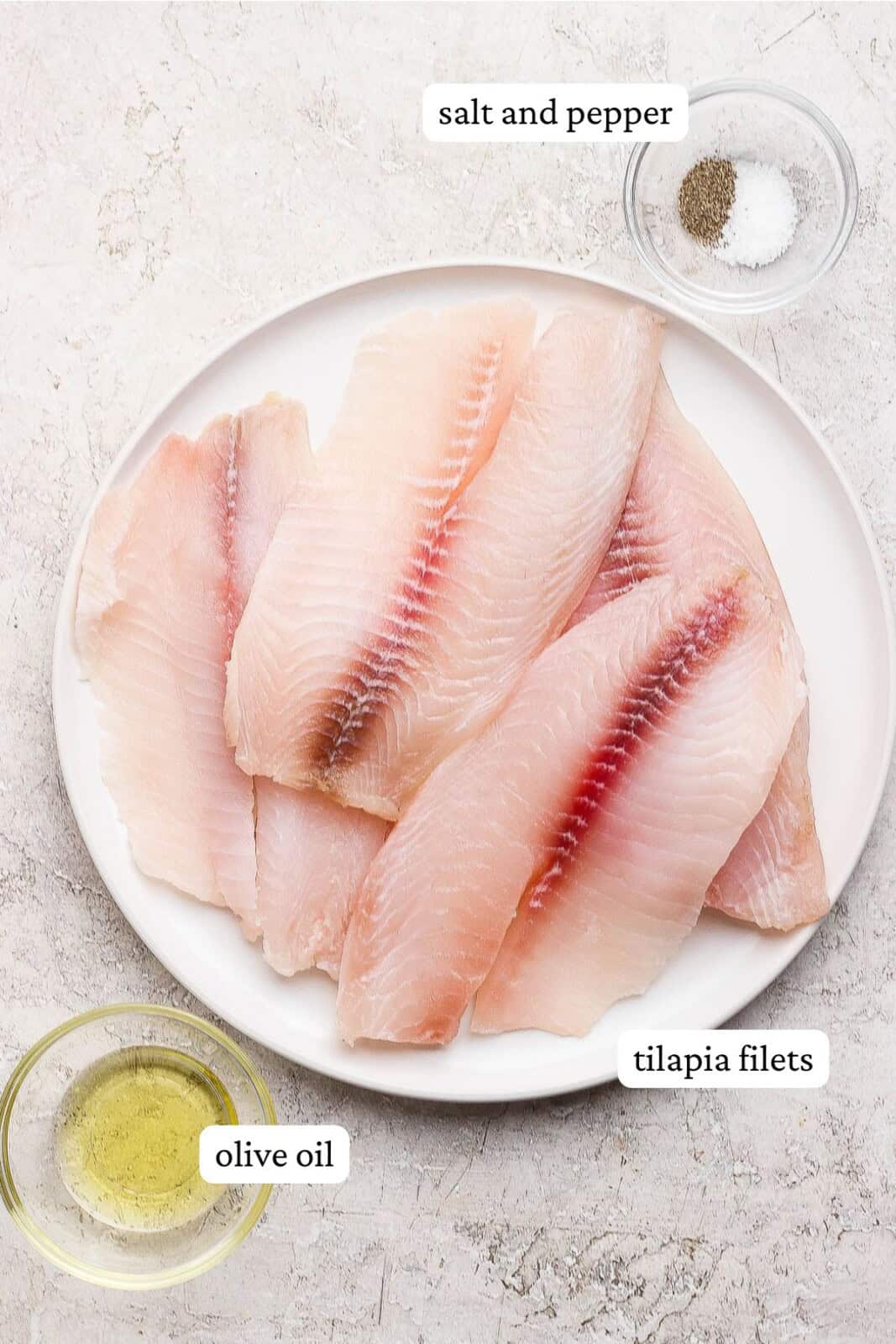 Ingredients for oven baked tilapia labeled and separated out on plates and in bowls. 