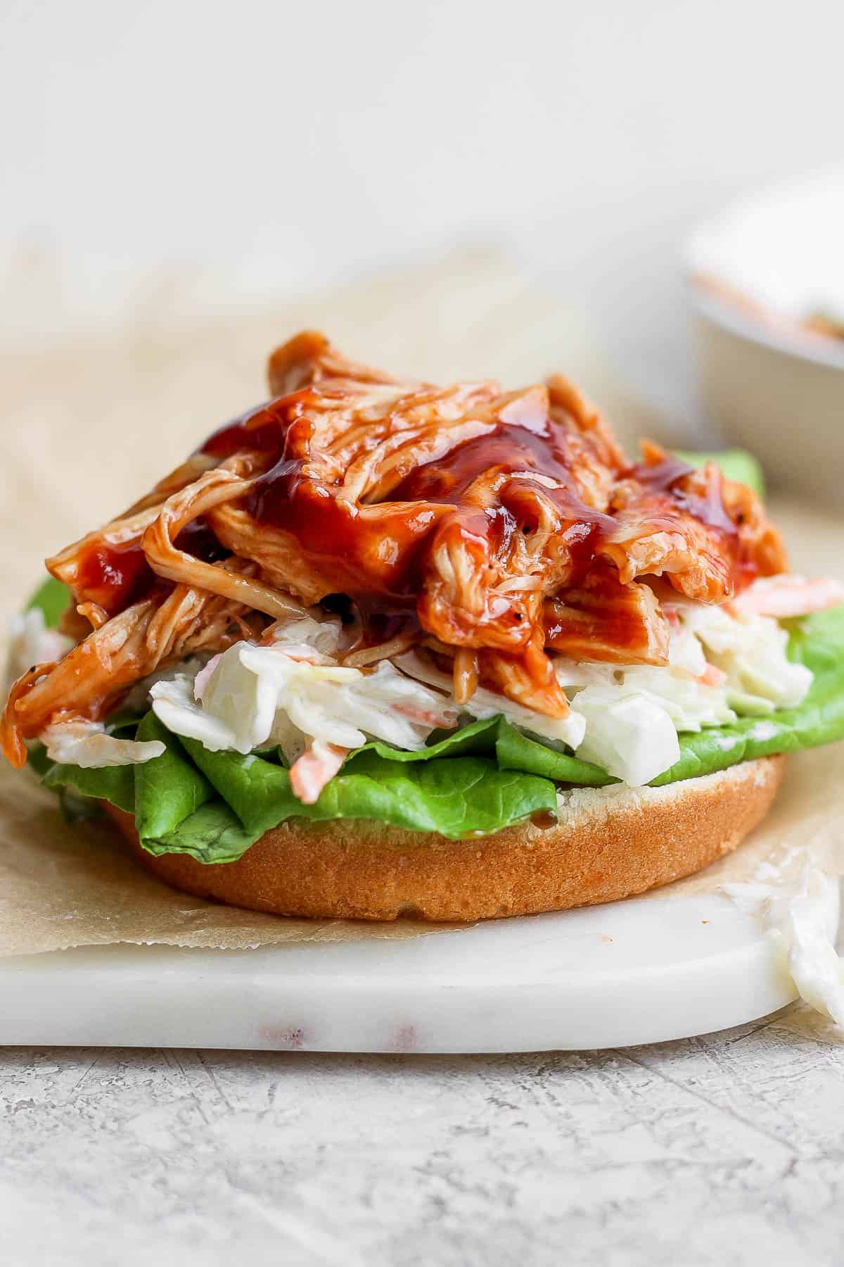 BBQ chicken on a bun with coleslaw and lettuce.