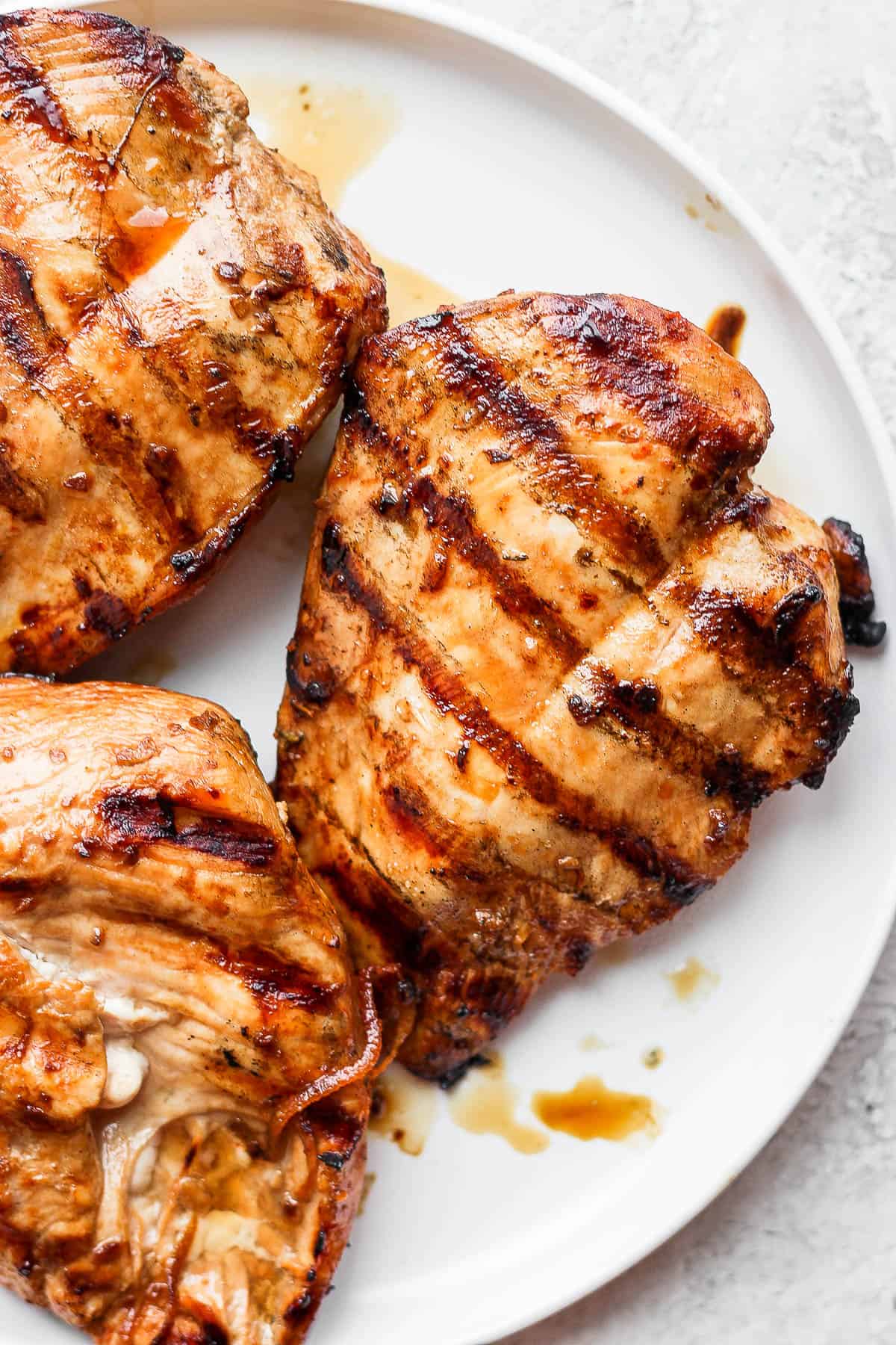 Grilled chicken breasts on a white plate.