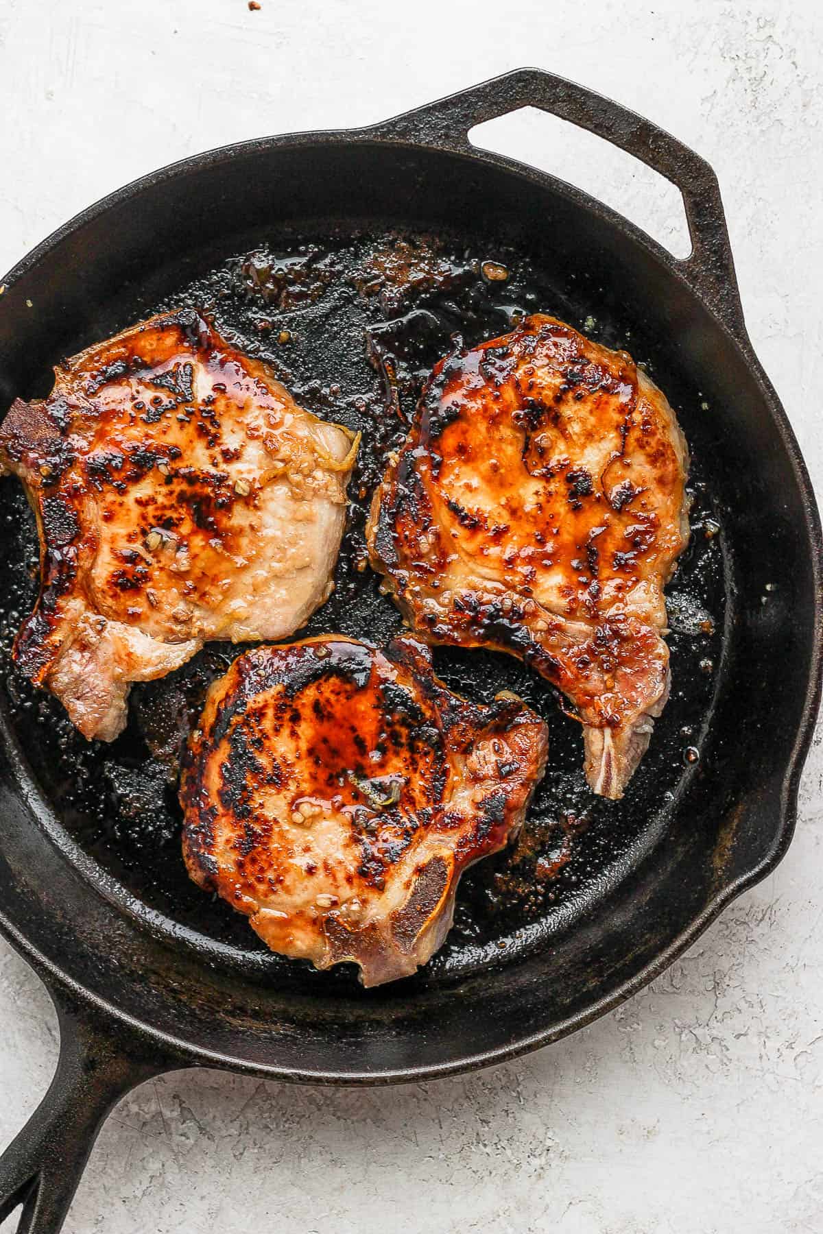 Seared pork chops in a cast iron skillet.