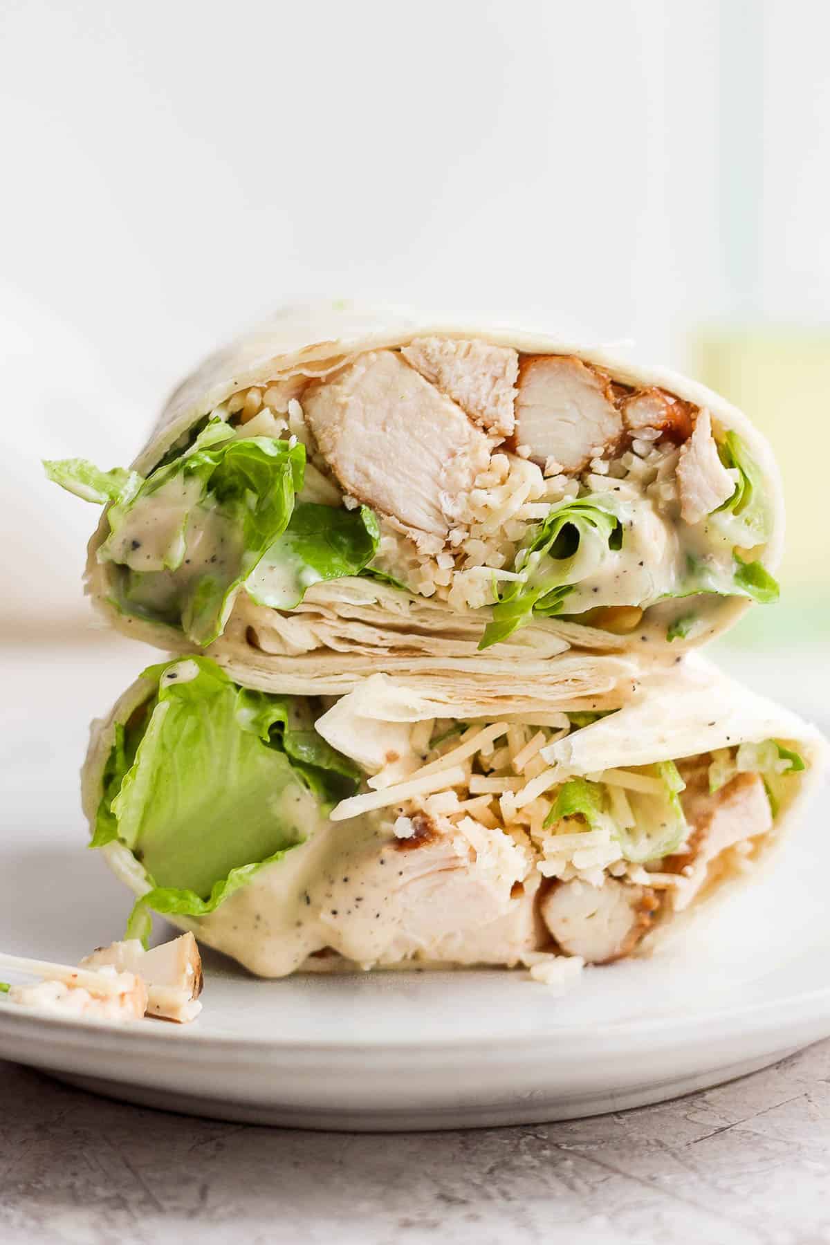 Two halves of a chicken caesar wrap on a plate.