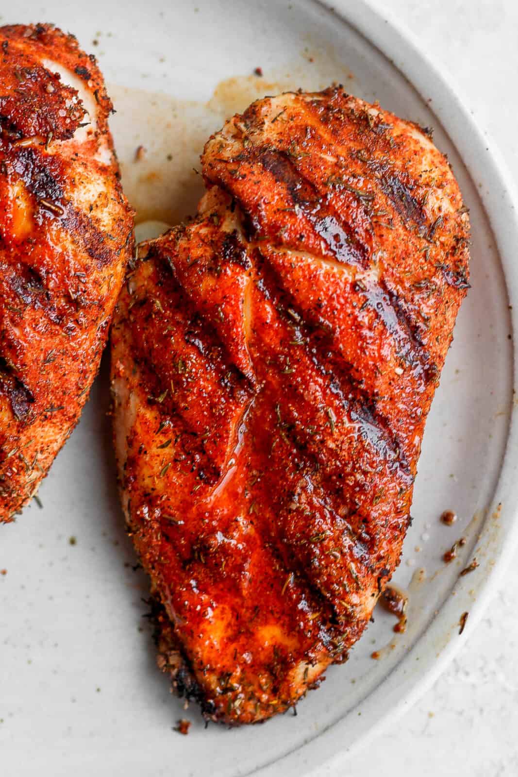 Seasoned chicken breasts that were grilled on a plate.