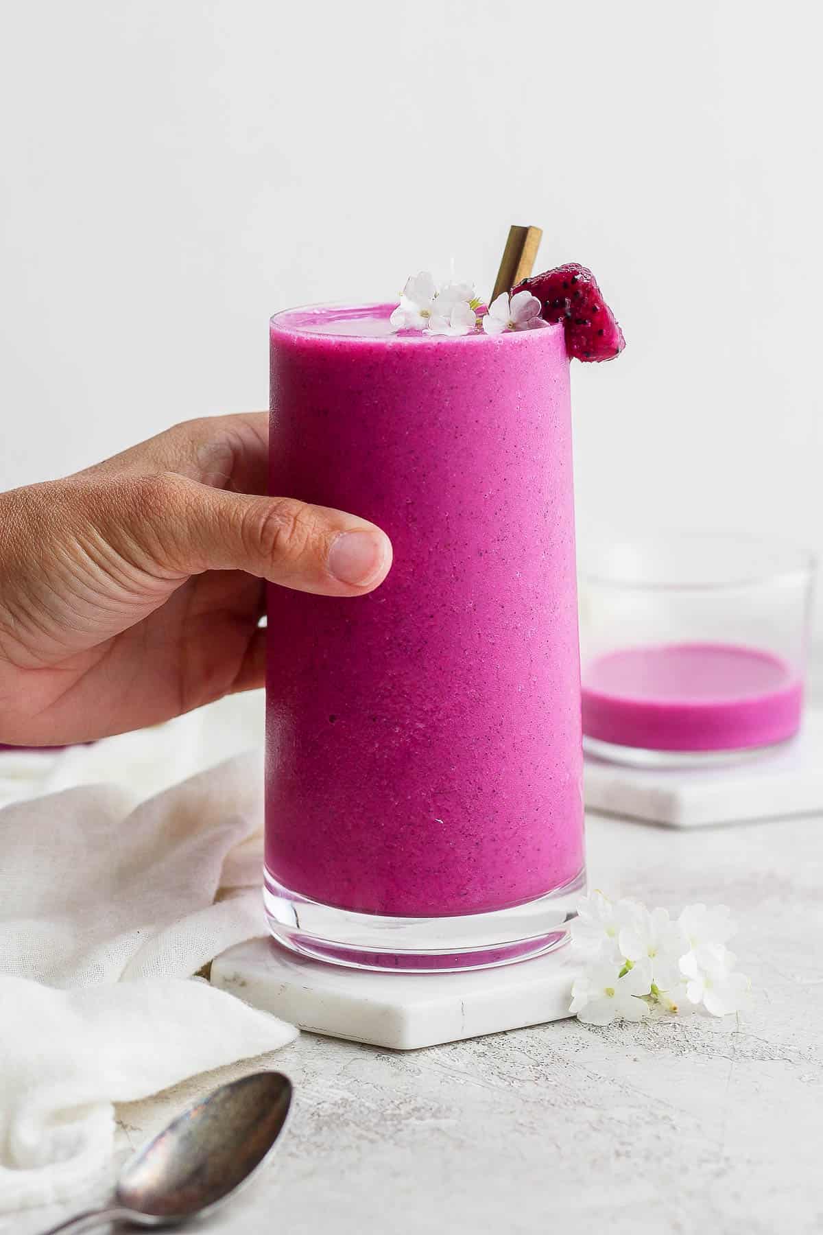 A hand grabbing a dragonfruit smoothie.