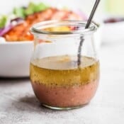 Greek vinaigrette in a small jar with a spoon.