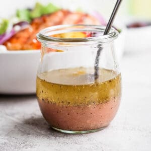 Greek vinaigrette in a small jar with a spoon.