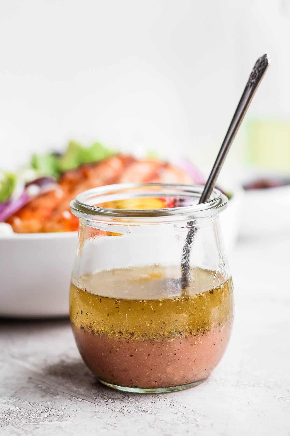 Greek vinaigrette in a jar with a spoon.