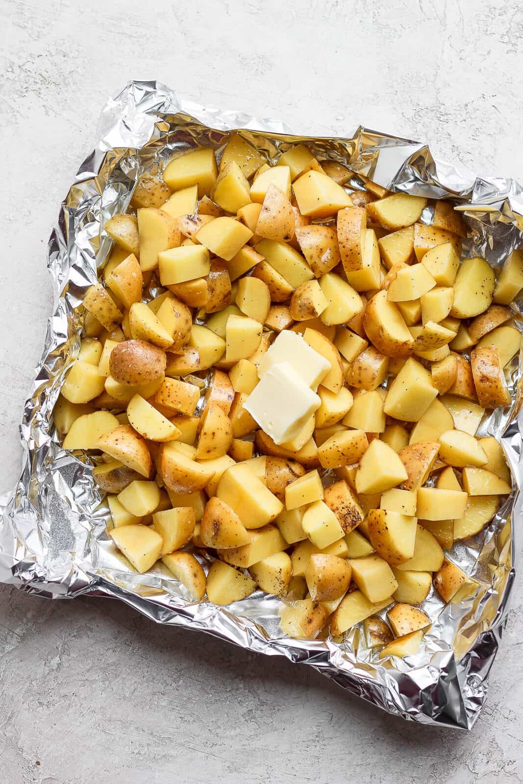 Cut up potatoes in a foil boat with oil, salt, pepper, and butter on top.