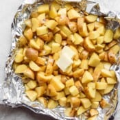 Cubed potatoes in aluminum foil with 2 tabs of butter.