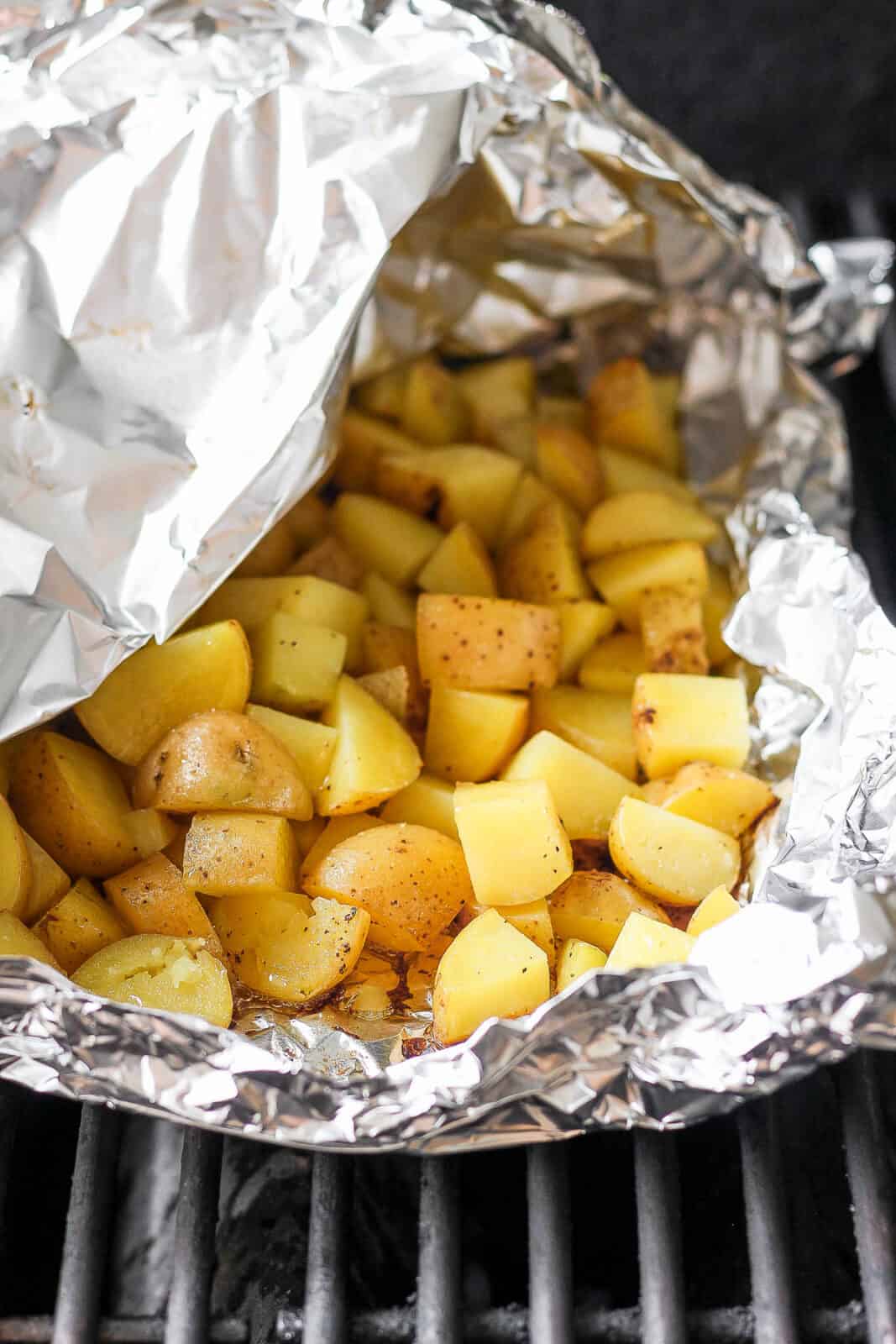 Grilled potatoes in a foil boat on the grill.