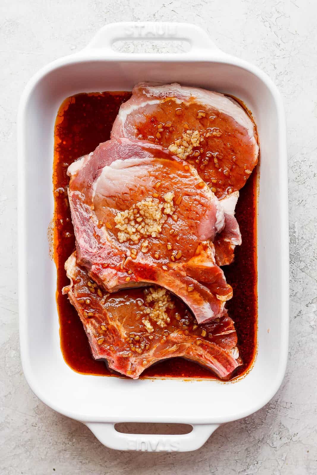 Three pork chops in a marinade. 