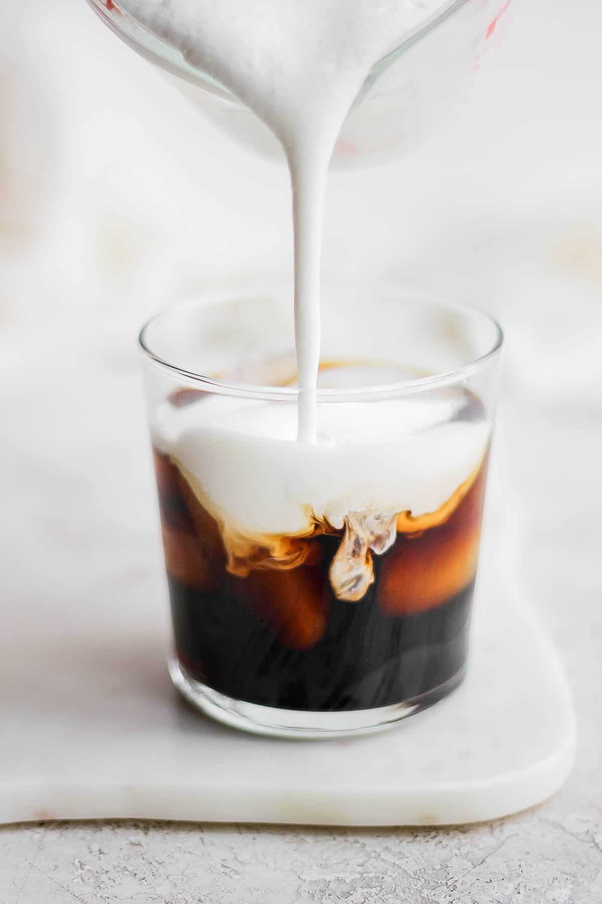 Sweet Cream Cold Foam pouring into a cup of cold brew.