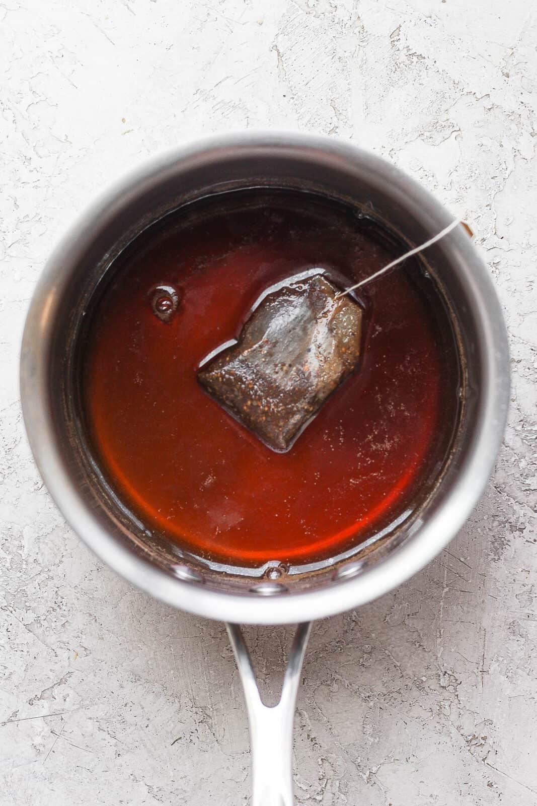 Chai tea in a small saucepan with tea bag.