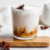 An iced chai tea latte on a board with some star anise.
