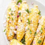 A platter filled with 5 grilled mexican street corns.