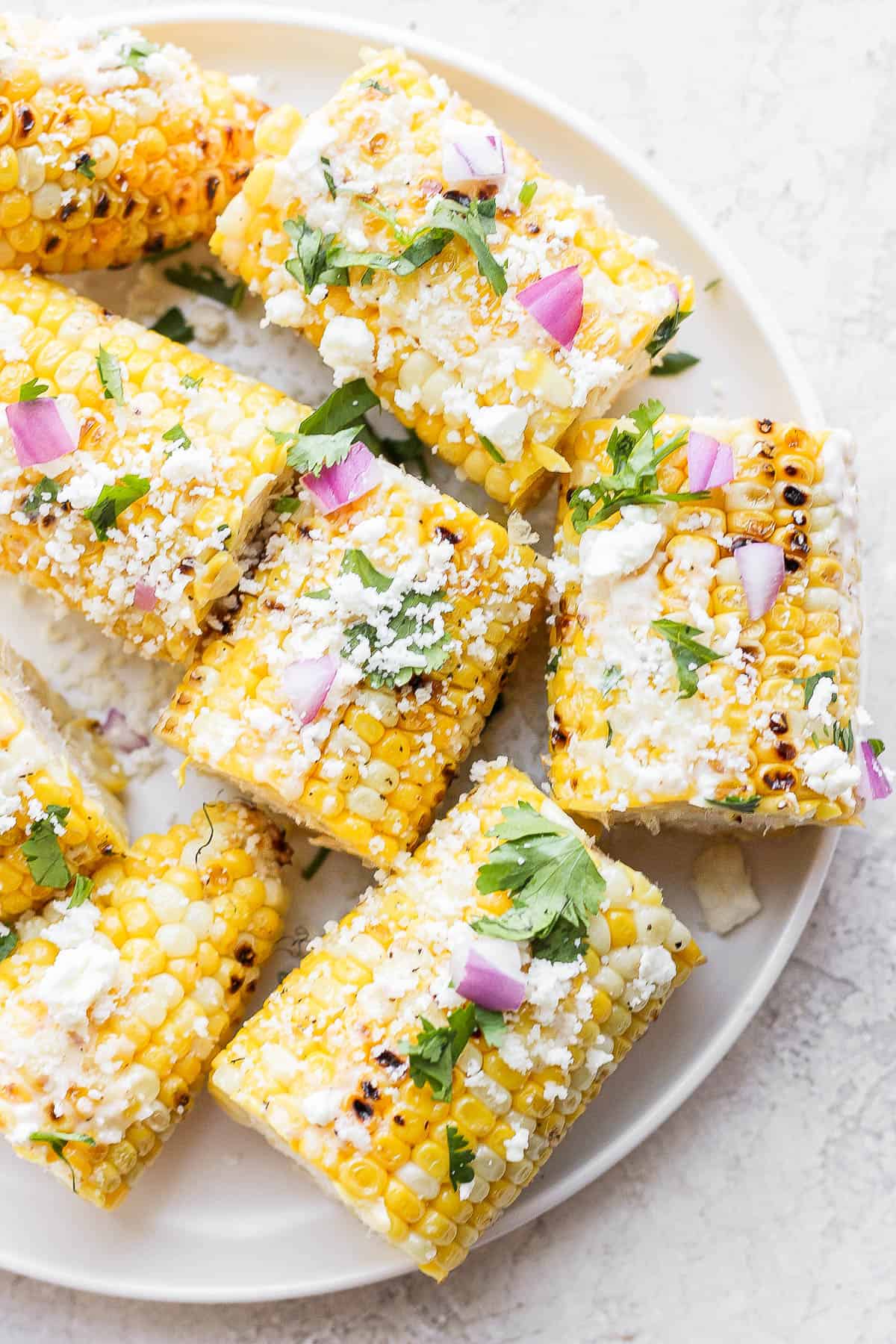 Mexican street corn cut into small cob pieces on a plate.