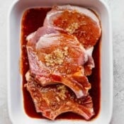 An all-purpose pork chop marinade in a baking dish with three bone-in pork chops.