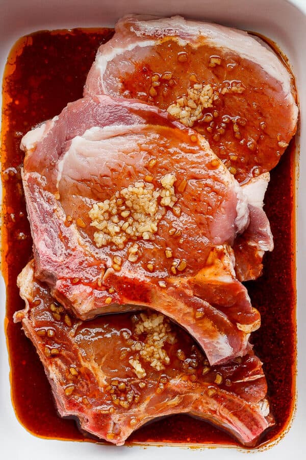 An all-purpose pork chop marinade in a baking dish with three bone-in pork chops.