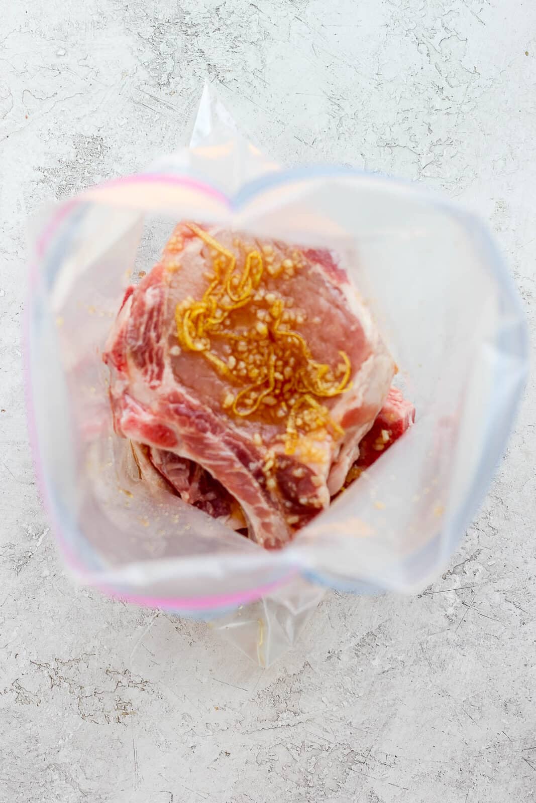 Honey garlic marinade ingredients with pork chops in a plastic bag.