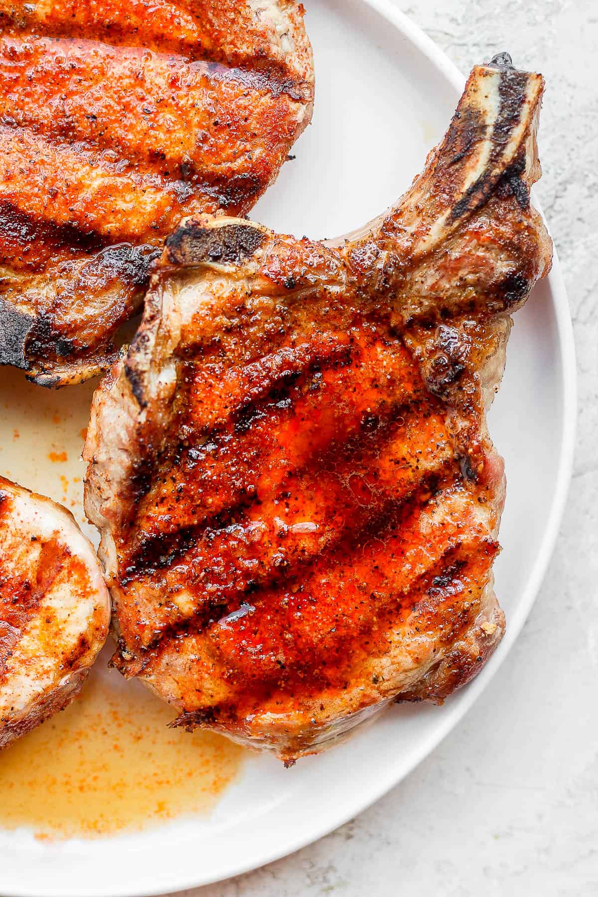 Seasoned pork chops on a plate after being grilled.