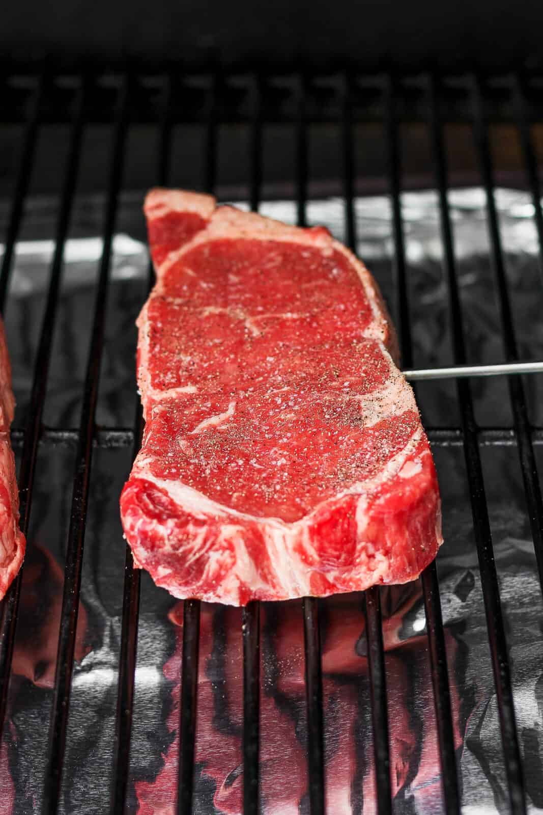 A raw steak on a smoker. 