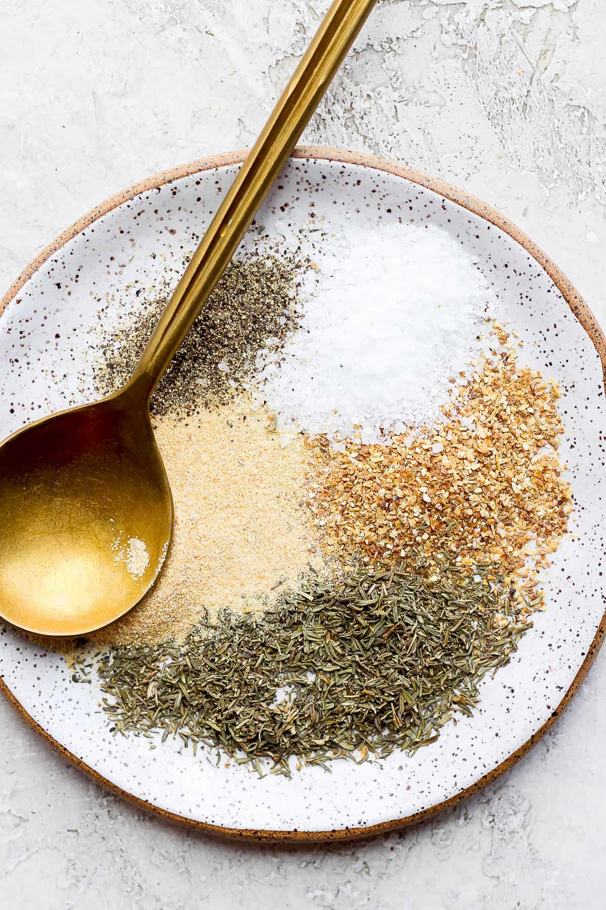 Seasoning ingredients on a plate with a spoon before mixing.